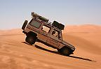 Ein Mercedes G nimmt dynamisch eine Düne im Erg Ubari (Libyen)